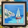 Evasion bleue - Encadré Peinture marine d'un voilier rouge près de falaises rocheuses dans une caisse américaine noire